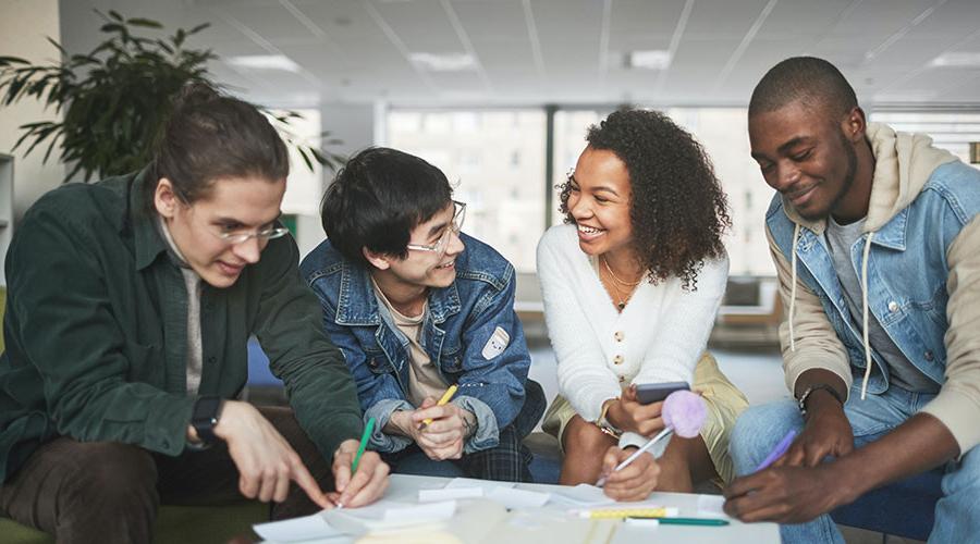 Four students talking and taking notes