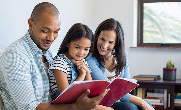 a family of three reading a book to their daughter